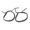 Two black beaded bracelets with blue evil eye charms on a white background