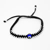 Black bracelet with a blue evil eye bead on a white background