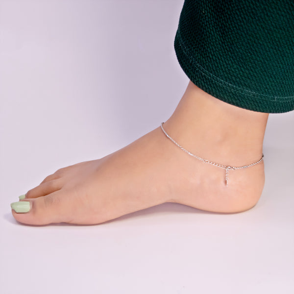 Silver anklet on a foot with a plain background