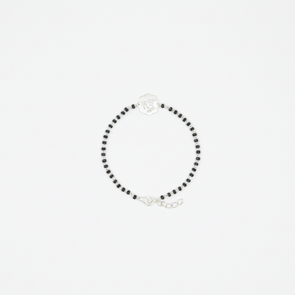 Black beaded bracelet featuring a silver flower charm displayed on a white background.