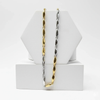Two gold and silver chain necklaces on a white geometric display stand.