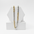 gold and silver chain necklaces on a white geometric stand against a white background