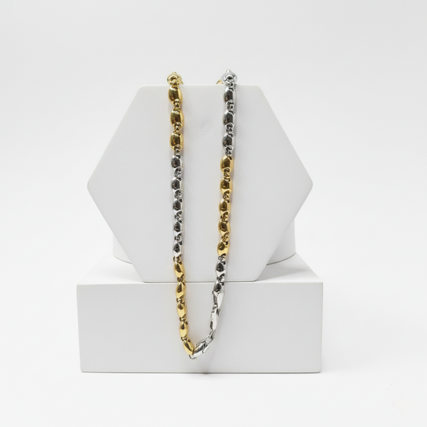 gold and silver chain necklaces on a white geometric stand against a white background