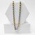Two-tone gold and silver chain necklace on a white hexagonal stand.