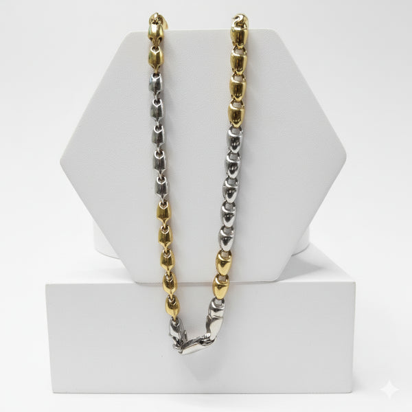Two-tone gold and silver chain necklace on a white hexagonal stand.