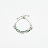 Vintage silver bracelet featuring emerald-green stones and antique-style detailing displayed on a white background.