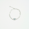 Silver bracelet with blue Evil Eye charm and leaf-shaped links displayed on a white background.