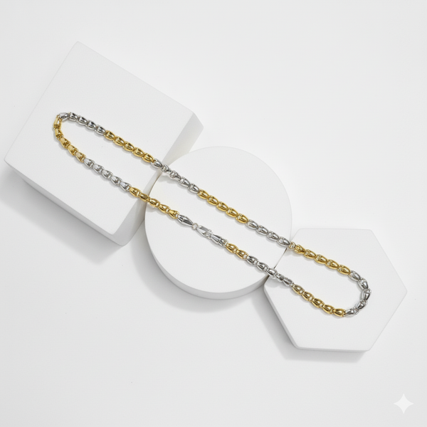 Two tone gold and silver chain necklaces on a white geometric stand.