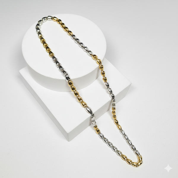 Gold and silver chain necklace on a white stand with a white background