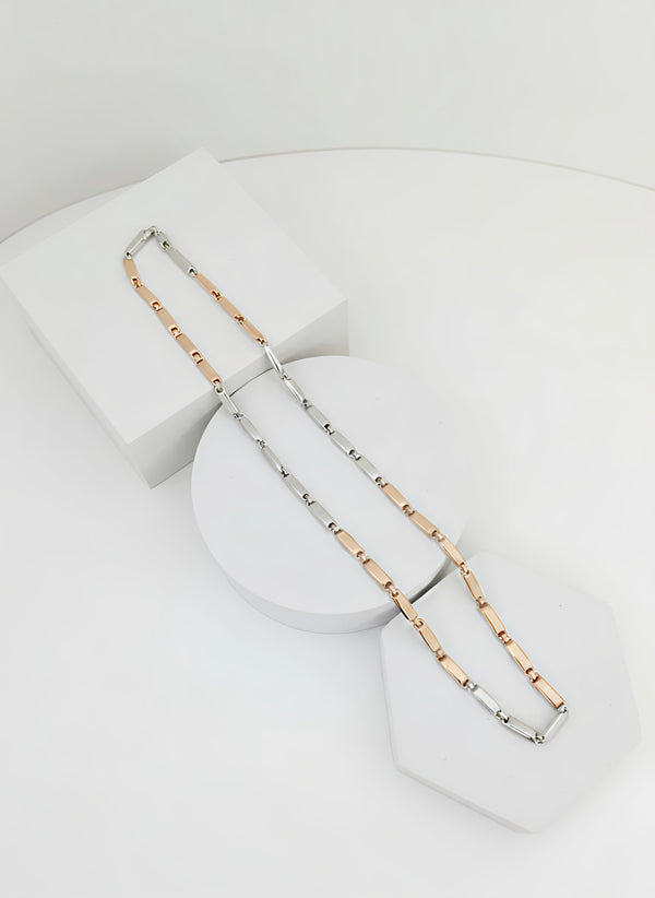 Two tone necklace, one silver and one rose gold, on a white stand.