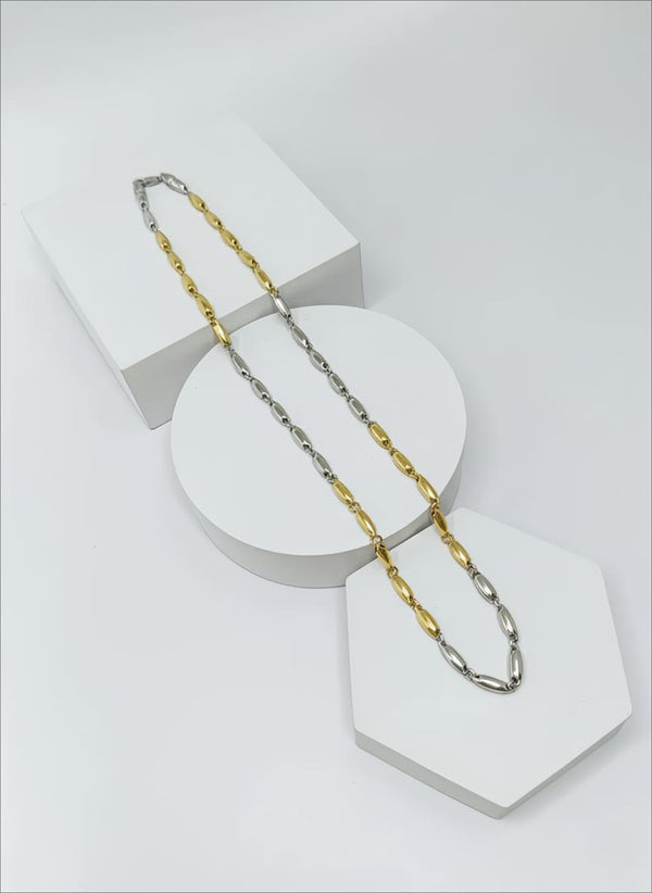 Gold and silver chain necklace on a white geometric stand