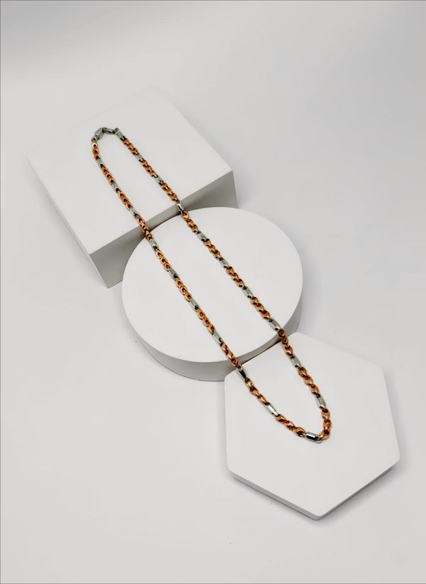 two tone silver and gold chain Necklace on a white geometric display stand against a light gray background