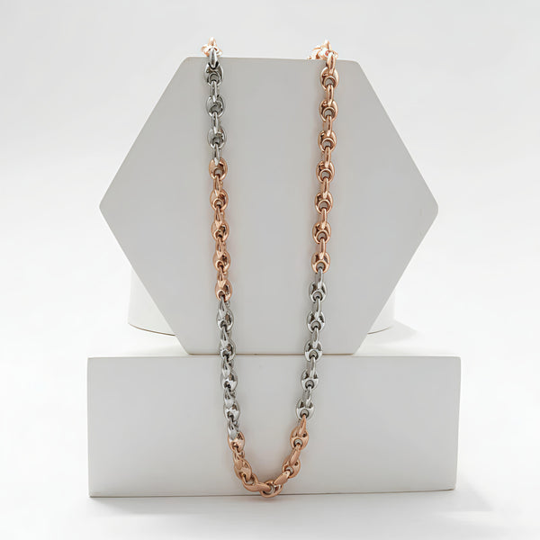 Two chain necklaces in rose gold and silver on a hexagonal white stand.