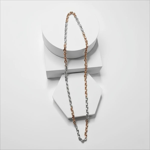 Two tone silver and gold necklace chain on a white surface with a neutral background