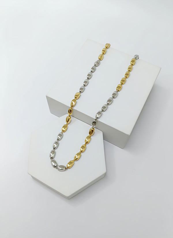 two-tone silver and gold chain necklace on a white stand with a white background