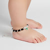 Pair of silver-plated black beaded anklets with green floral charm pendants, handcrafted traditional Indian jewelry for kids, adjustable thread design displayed on white background.