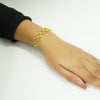 Gold bracelet on a wrist against a white background