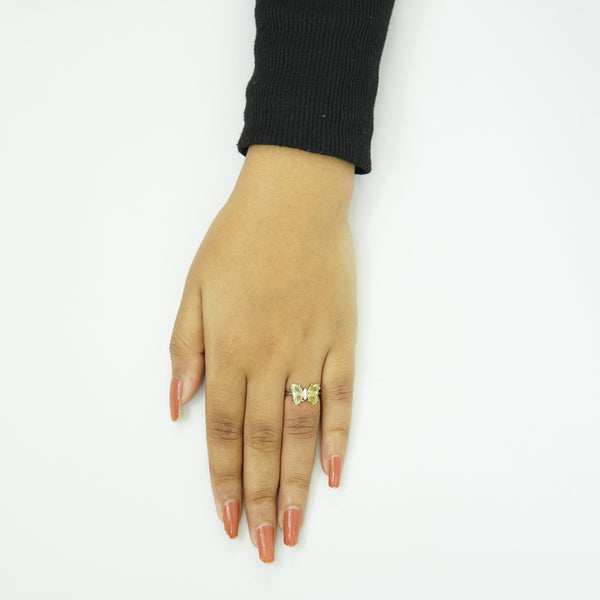 Elegant silver butterfly ring with twin green gemstones, adjustable women’s jewelry piece displayed on hand with nude manicure, luxury fashion accessory.