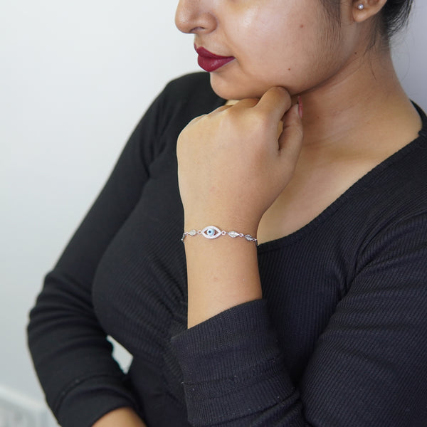 Woman wearing a silver Evil Eye bracelet with leaf-shaped links on her wrist.