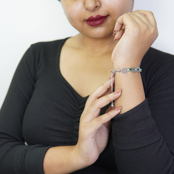 Woman wearing a vintage silver bracelet with green stones while posing in a black top.