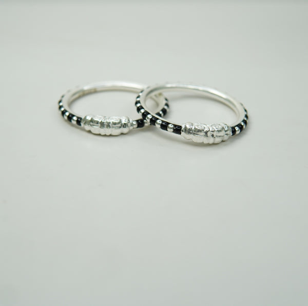 Two kids silver bangles with black beads on a light gray background
