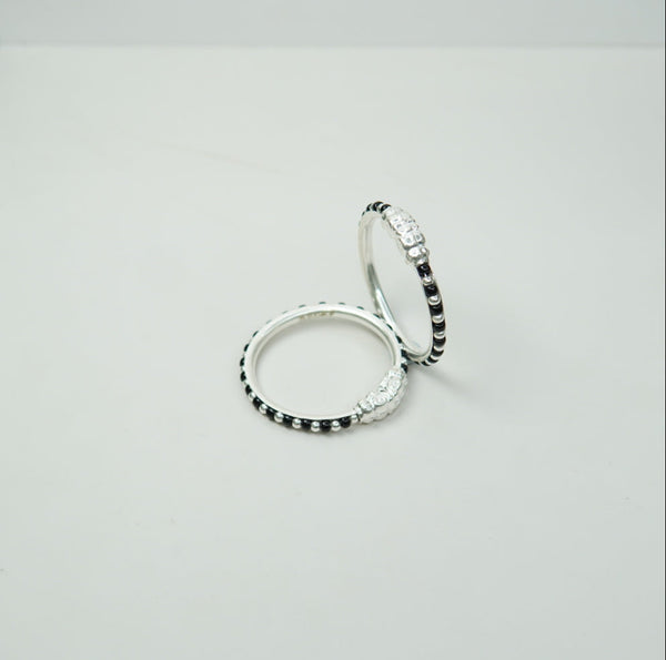 Two silver kids bangle with black beads on a white background
