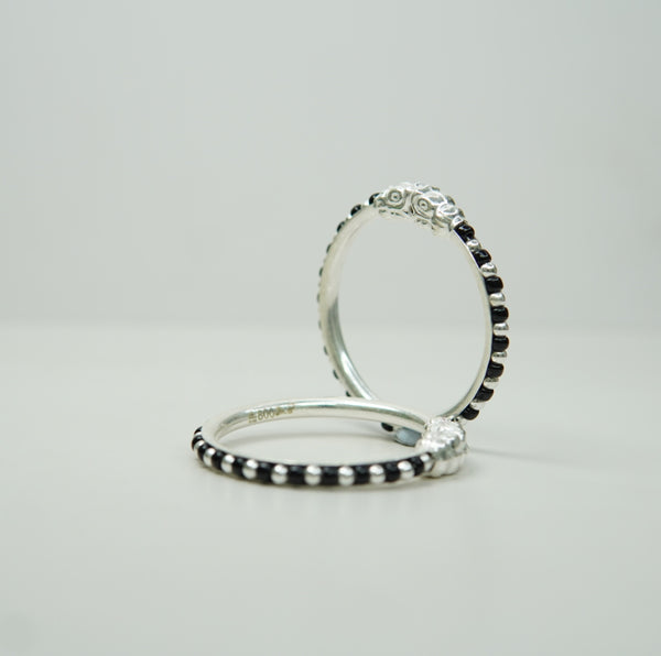 Two silver kids bangle with black beads on a light gray background