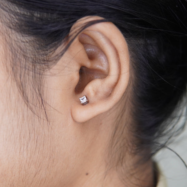 Close-up of an ear wearing a small diamond earring.