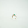 Gold ring with a green gemstone on a light gray background