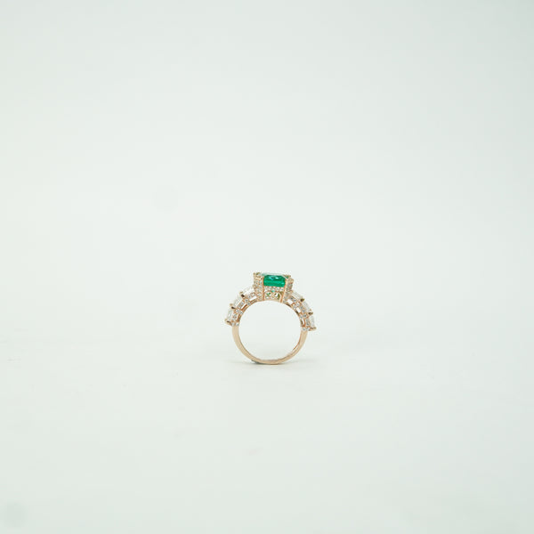 Gold ring with a green gemstone on a light gray background