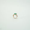 Gold ring with a green gemstone on a light gray background