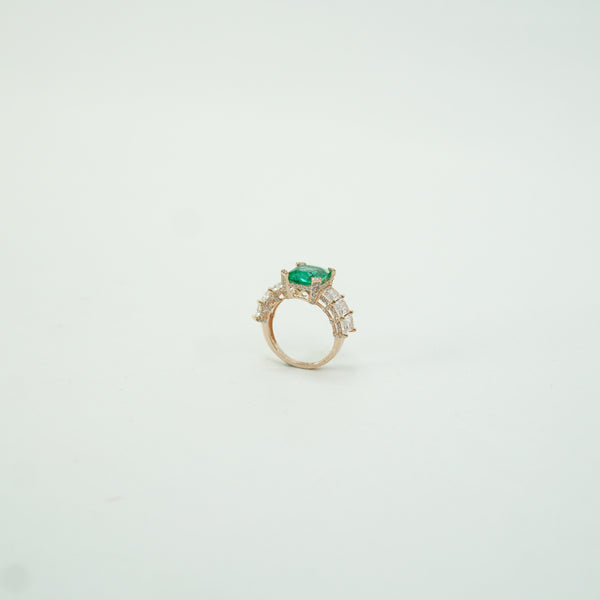 Gold ring with a green gemstone on a light gray background