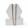 Two tone silver and gold chain necklaces on a white geometric stand with a white background