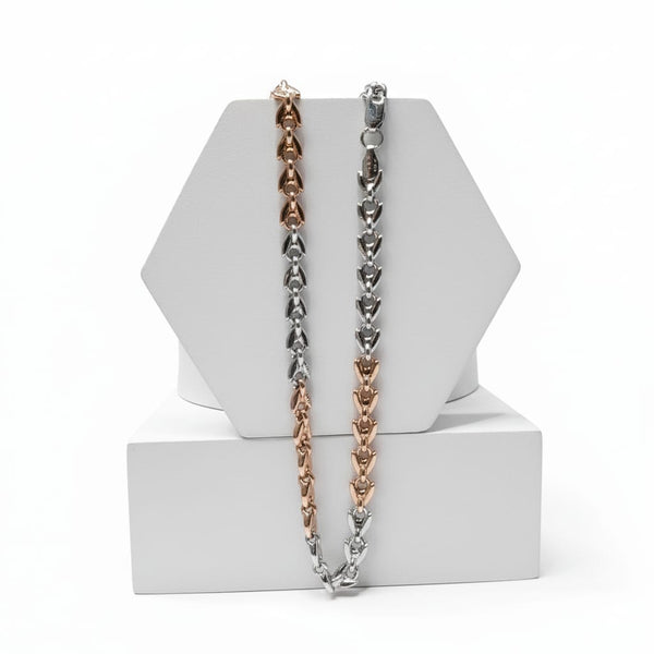 Two tone silver and gold chain necklaces on a white geometric stand with a white background