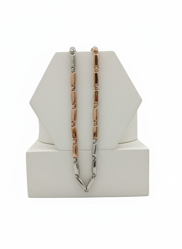Two tone silver and gold chain necklaces on a white geometric display stand
