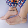 Silver Anklet on a person's ankles with a patterned garment.
