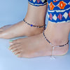 silver anklets on feet with a blue background