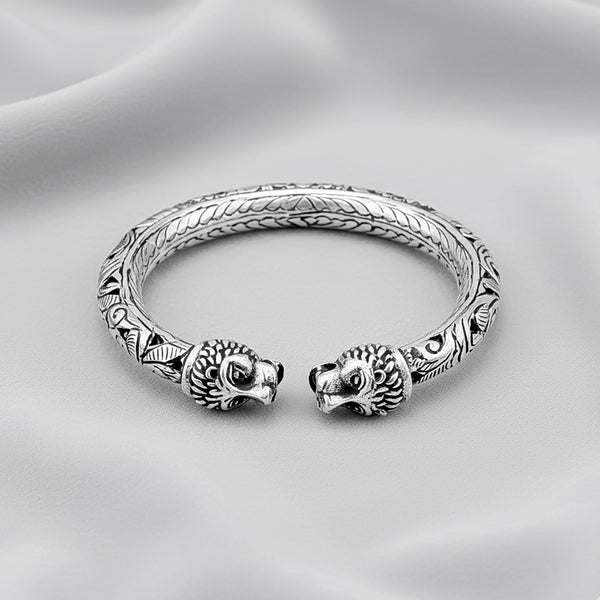 Silver bracelet with lion head designs on a gray background