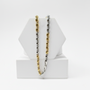 gold and silver chain necklaces on a white geometric stand against a white background 