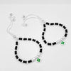 Pair of silver-plated black beaded anklets with green floral charm pendants, handcrafted traditional Indian jewelry for kids, adjustable thread design displayed on white background.