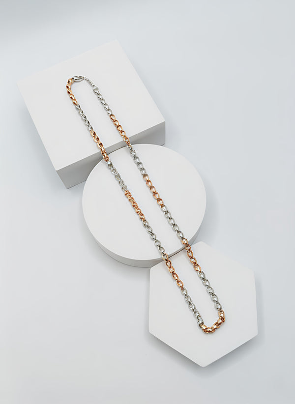 Two tone necklace chain with silver and gold on a white geometric stand with a light gray background