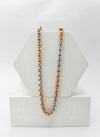 Two-tone chain necklace in silver, rose gold, and gold on a white stand.