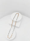 Two-tone silver and goldnecklace on a white stand with a light gray background