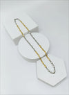 Gold and silver chain necklace on a white geometric stand