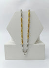 Two tone gold and silver chain necklaces on a white hexagonal stand.