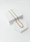 Gold chain necklace on a white stand with a white background