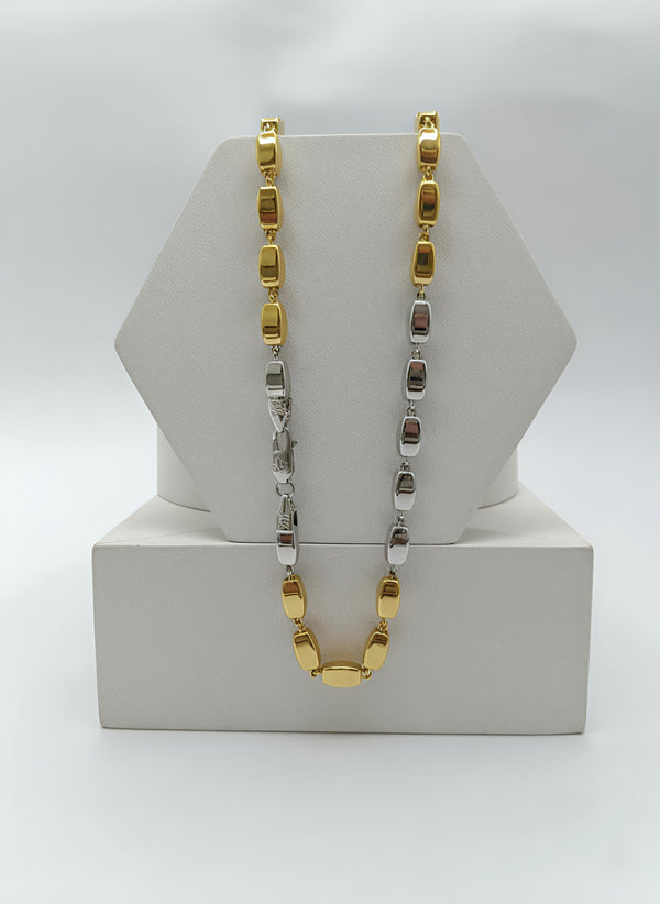 Gold and silver chain necklace on a white stand with a white background