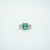 Emerald ring with diamond accents on a light gray background